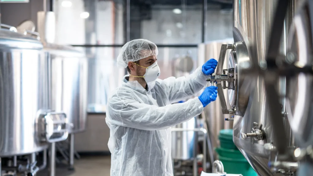 Opérateur en tenue de protection sur une cuve industrielle agroalimentaire